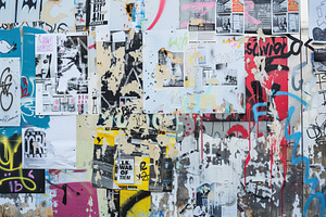 A Vibrant Urban Wall Covered With A Mix Of Posters, Graffiti, And Paint Splatte