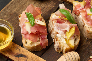An arrangement of bruschetta with prosciutto, pear and cheese, s, a Food & Drink Photo by ndanko