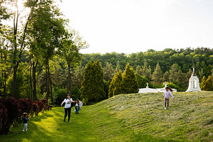 Family enjoying a sunny walk along a lush green park pathway, a Photo by AS photostudio