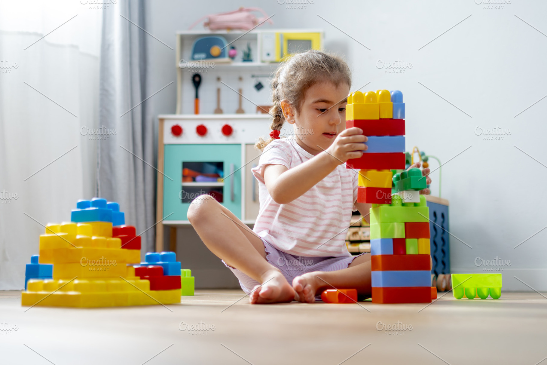 Little girl building colorful block tower on floor at home, a Person Photo by etorres69
