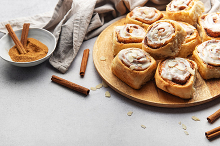 Freshly baked cinnamon rolls with icing and almond flakes on woo, a Food & Drink Photo by Olena Rudo