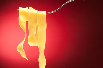 Fork with tagliatelle on a red background