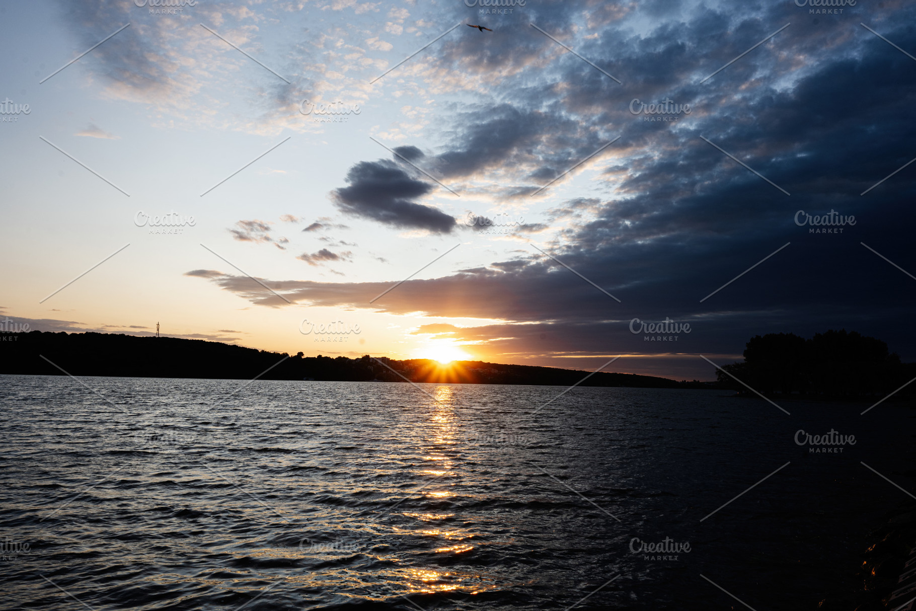 Serene sunset over a calm lake with scattered clouds, a Photo by AS photostudio