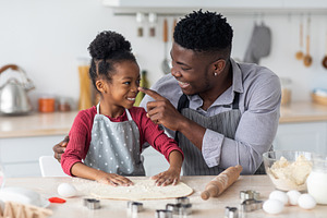 Loving african american family haivng fun while baking at home, a Photo by Prostock-Studio