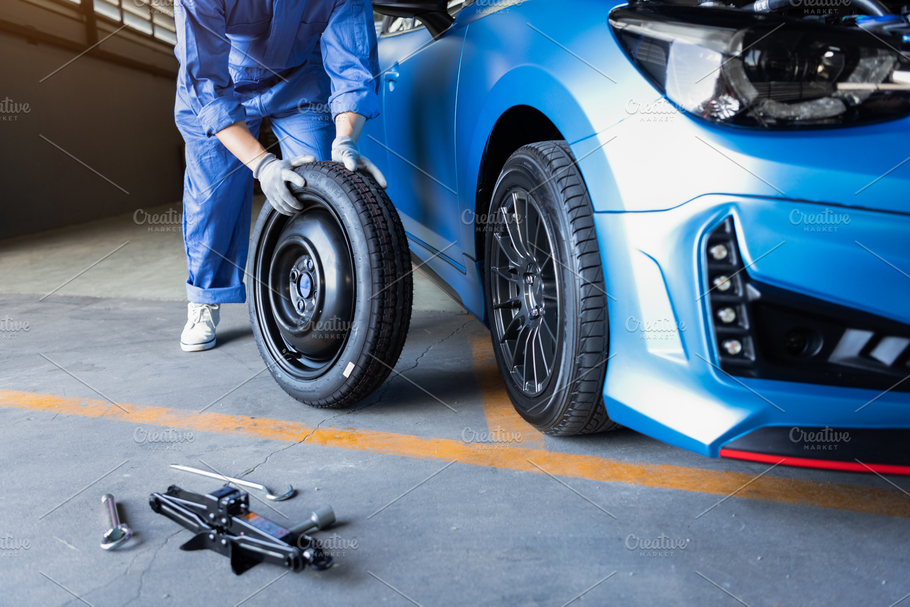 Car mechanics changing tire at auto repair shop garage. Transpor, an Industrial Photo by Ministocker