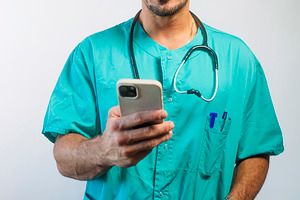Healthcare Worker Checking a Smartphone, a Person Photo by karrastock