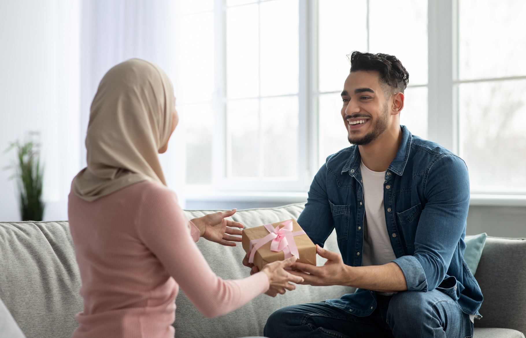 Handsome arab man giving gift box his wife, a Photo by Prostock-Studio
