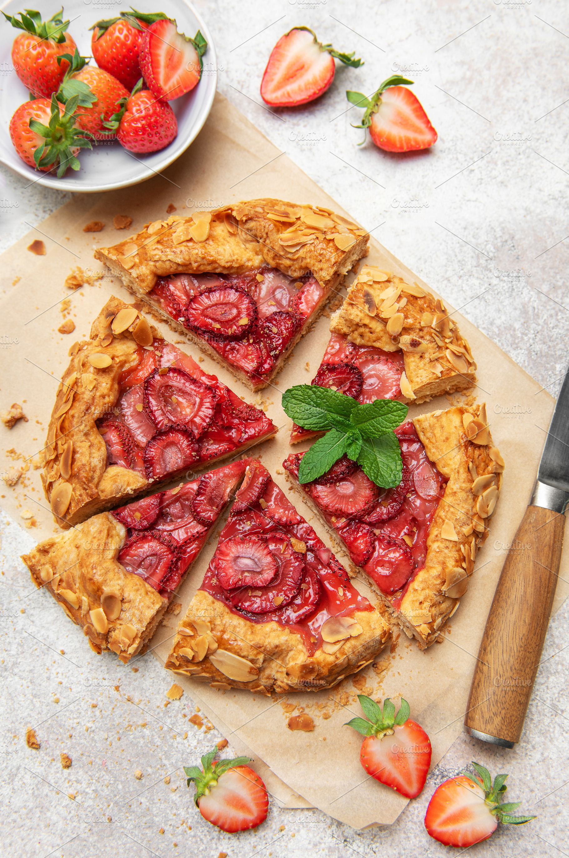 Delicious homemade strawberry galette with almond flakes being s, a Food & Drink Photo by Olena Rudo