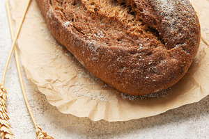 Rye bread loaf with wheat ears on parchment paper, a Food & Drink Photo by Olena Rudo