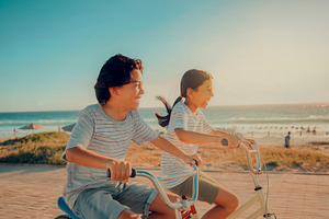 Two children riding bicycles by the beach, a Person Photo by DanFLCreativo