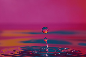 A close-up of a water droplet creating ripples in a colorful background. The dr, a Photo by Textures & Backgrounds