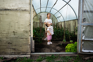 Two children enjoying time together inside a greenhouse surrounded by plants, a Person Photo by AS photostudio