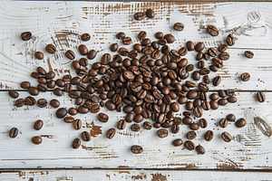 Heap of coffee beans on wooden table, a Food & Drink Photo by AlyaAnd