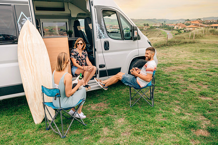 Friends with their dog talking and drinking beer in front of their camper van, a Holiday Photo by davidpereiras
