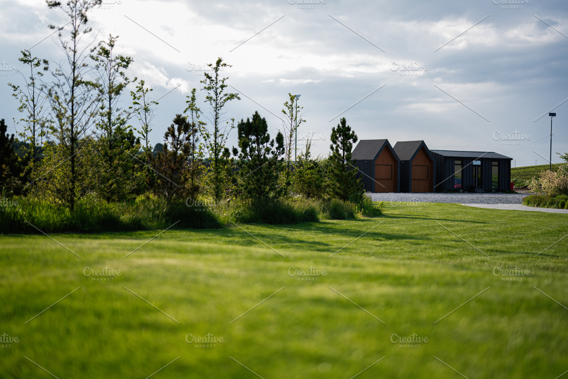 Modern cabins near green landscape with trees under cloudy sky, a Photo by AS photostudio