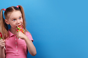 Happy girl in a pink shirt playfully biting into a bunch of colo, a Person Photo by Ales Munt