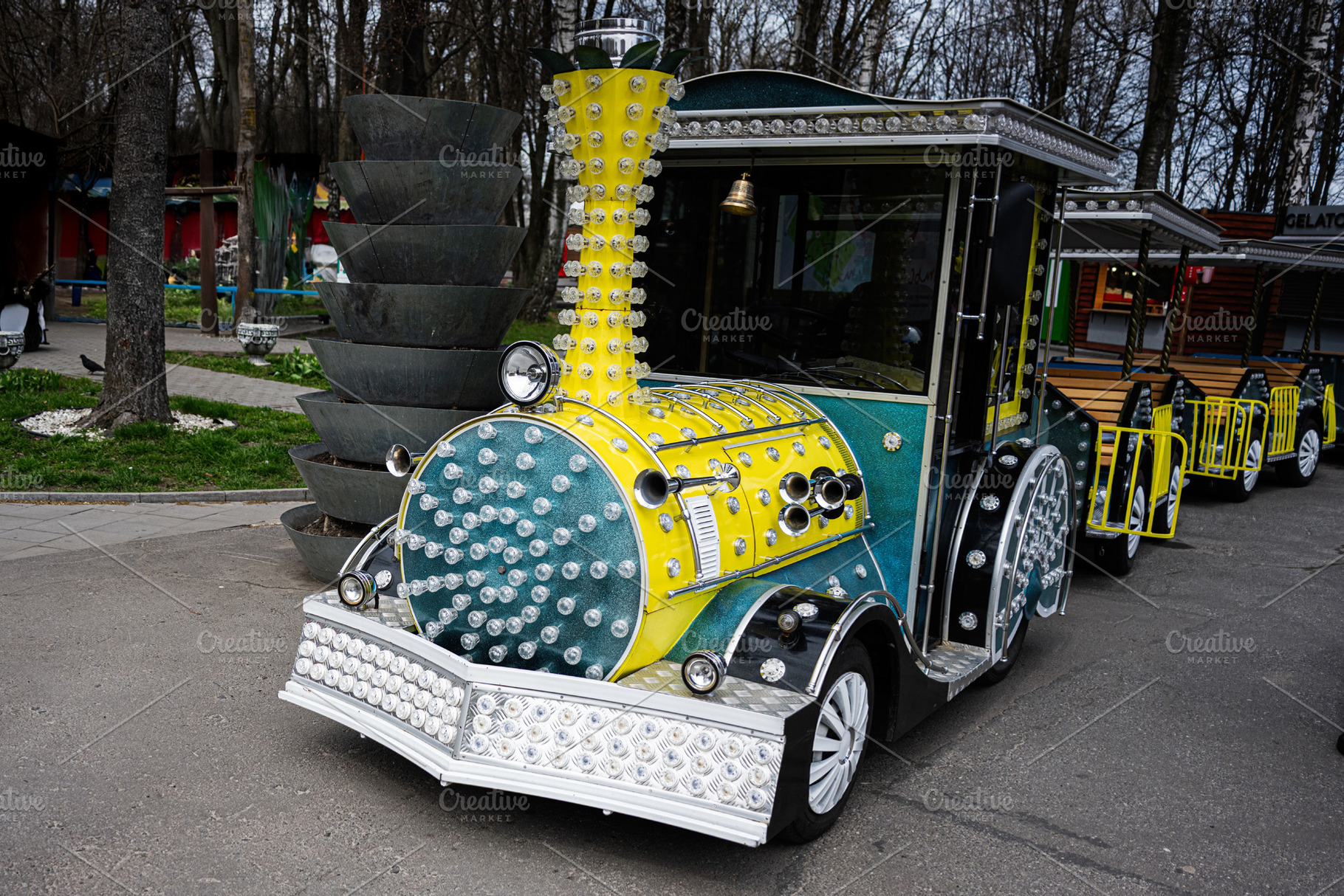 Colorful illuminated train cart in a park setting during daytime, a Photo by AS photostudio