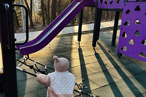 Child playing on a purple playground at sunset surrounded by trees, a Photo by AS photostudio