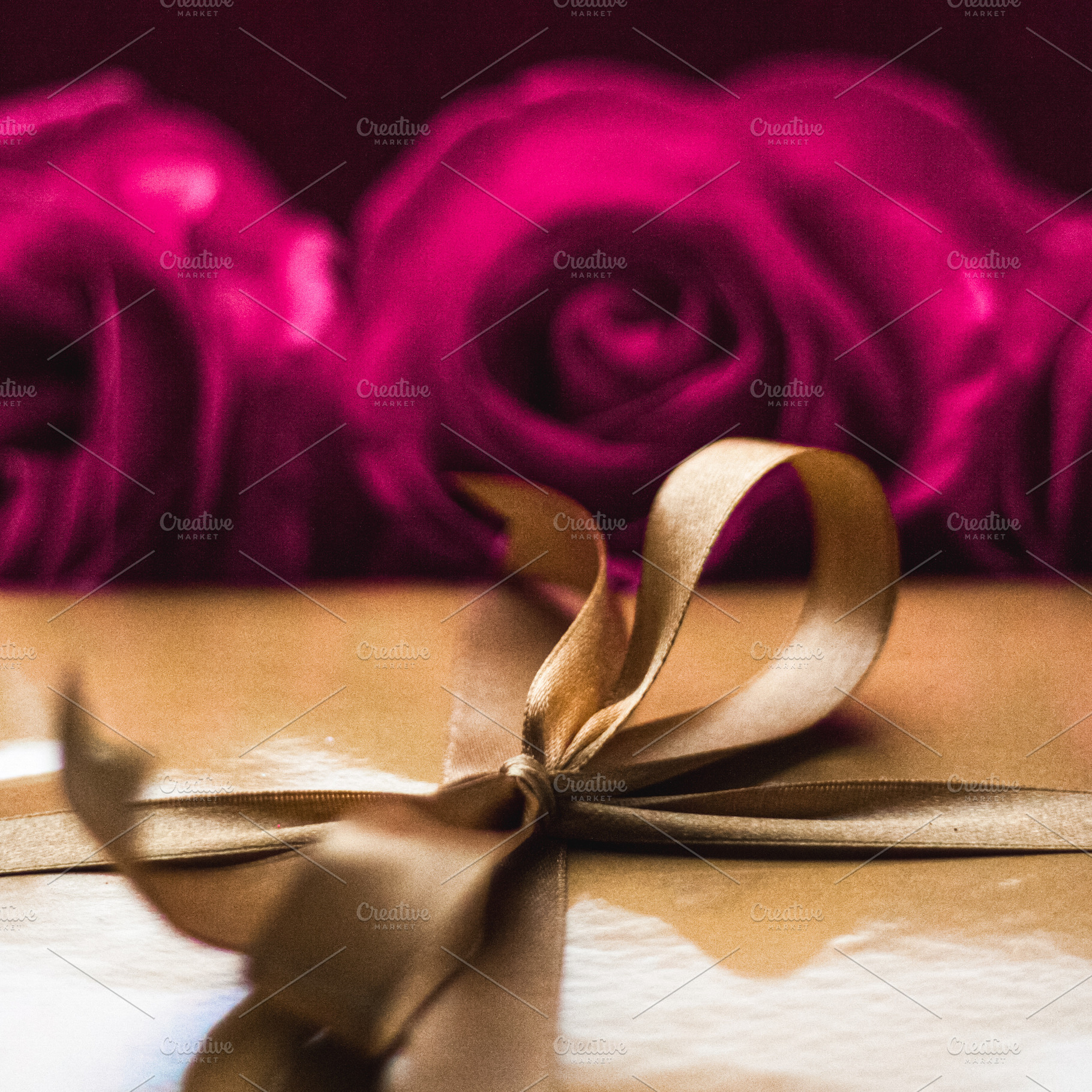 Golden gift box with a bow and red roses in the background, symb, a Photo by Studio ANNA