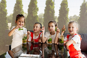 Group of children enjoying refreshing drinks together at an outdoor cafe settin, a Photo by AS photostudio