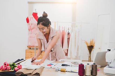 Attractive Asian female fashion designer working in home office, a Beauty & Fashion Photo by Ministocker