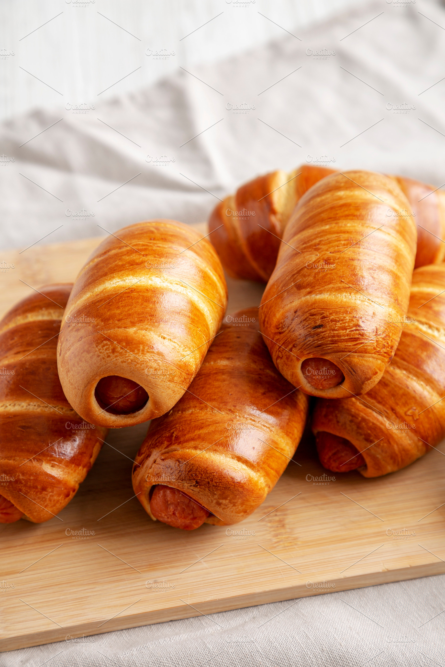 Homemade Sausage Buns on a bamboo board, side view., a Food & Drink Photo by LiudmylaChuhunova