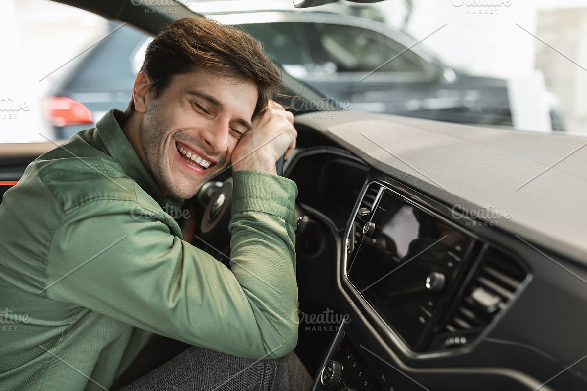 Delighted young man sitting in driver's seat, hugging steering wheel of his new, a Photo by Prostock-Studio (Photo 2 of 2)