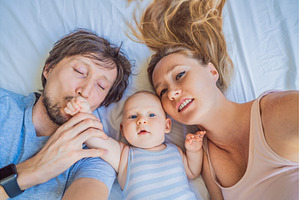 Baby lying with mother and father on, a Person Photo by Elizaveta Galitskaya
