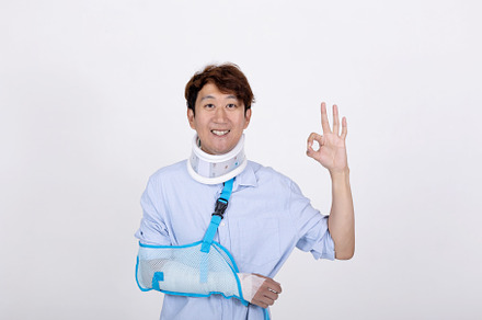 Smiling Asian man with broken arm and neck feeling showing okay