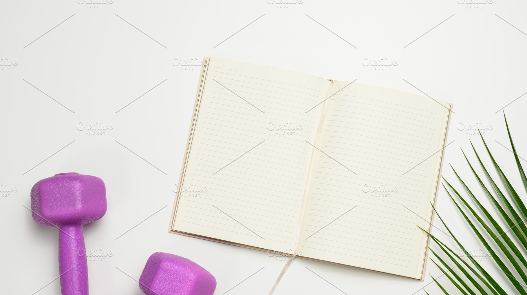 Open lined notebook with blank pages, surrounded by purple dumbb, a Sports & Recreation Photo by ndanko