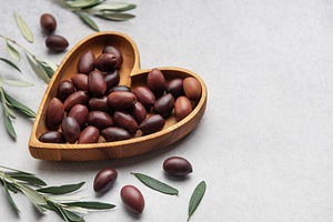 Heart shaped wooden bowl with fresh olives displayed, a Food & Drink Photo by Olena Rudo