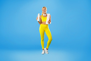 Sporty smiling woman posing at studio with water bottle, a Photo by Prostock-Studio