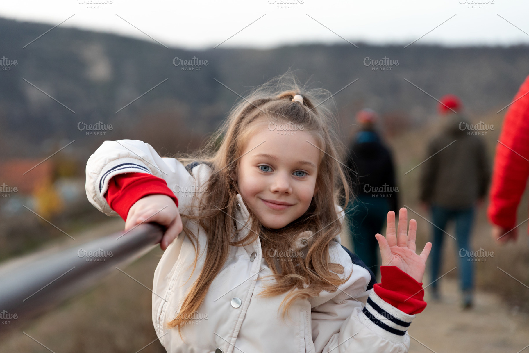 Cheerful young girl in a light jacket waving at the camera, stan, a Person Photo by Ales Munt