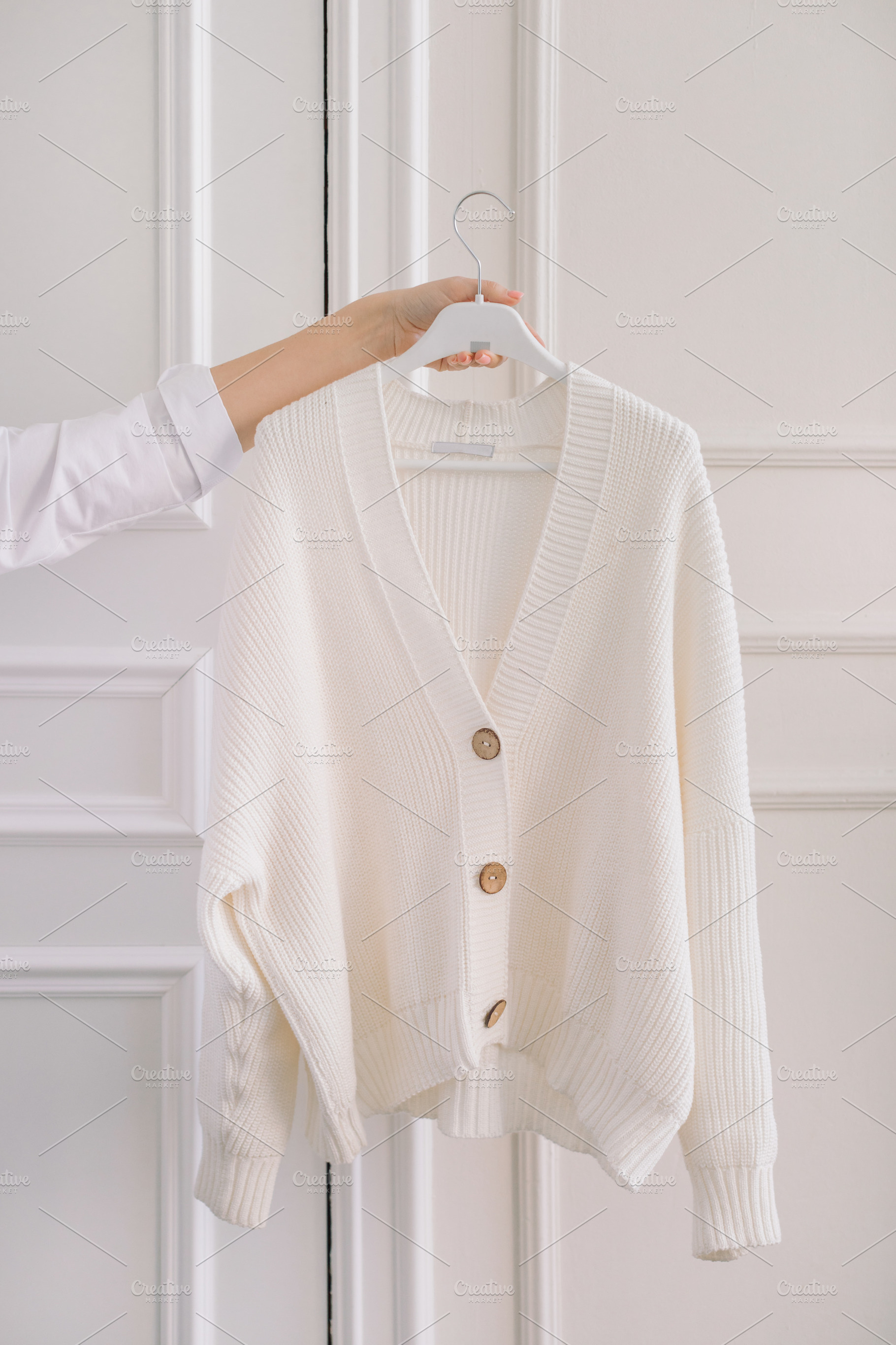 Arm holding out the white sweater, a Photo by Nina Stock Photos