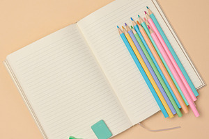 Top view of an open notebook with pastel-colored pencils, green, a School & Education Photo by ndanko