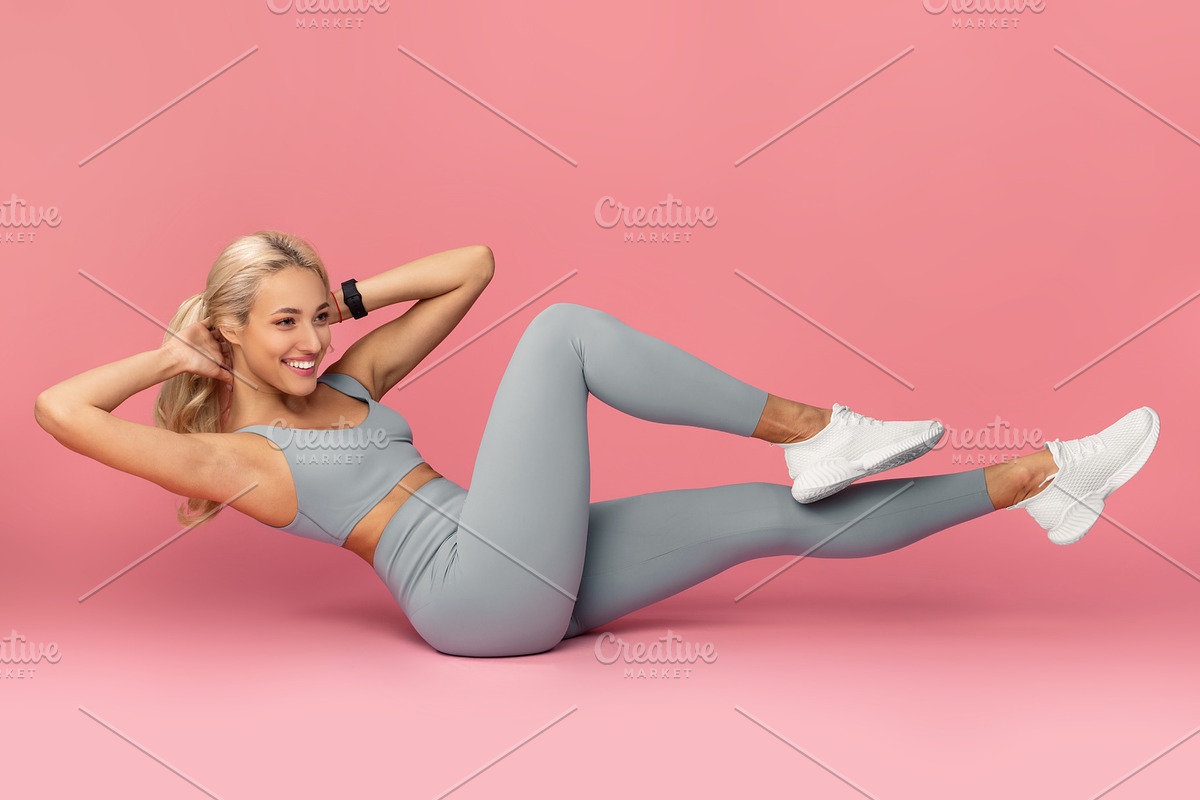 Smiling Young Woman Doing Abs Exercise, Side Crunches, a Photo by Prostock-Studio (Photo 2 of 2)