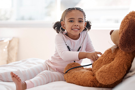 Children, stethoscope and teddy bear with a girl playing doctor in her bedroom at home with a stuffed animal. Imagination, healthcare and medicine with a cute female child being a pretend nurse, a Photo by Peopleimages.com