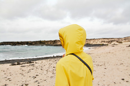 Girl on white beach in yellow jacket