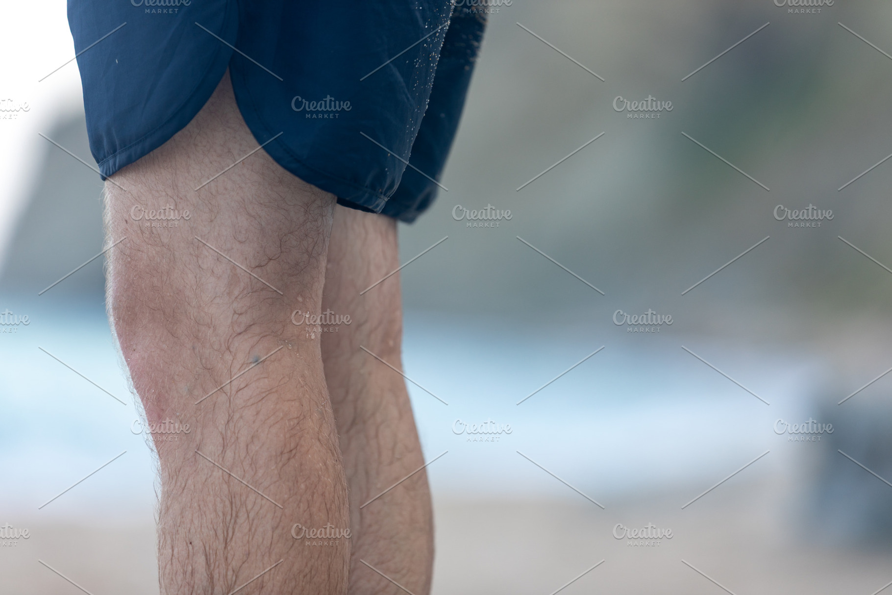Close-up of a man’s legs wearing navy shorts standing outdoors, with a blurre, a Nature Photo by Ales Munt