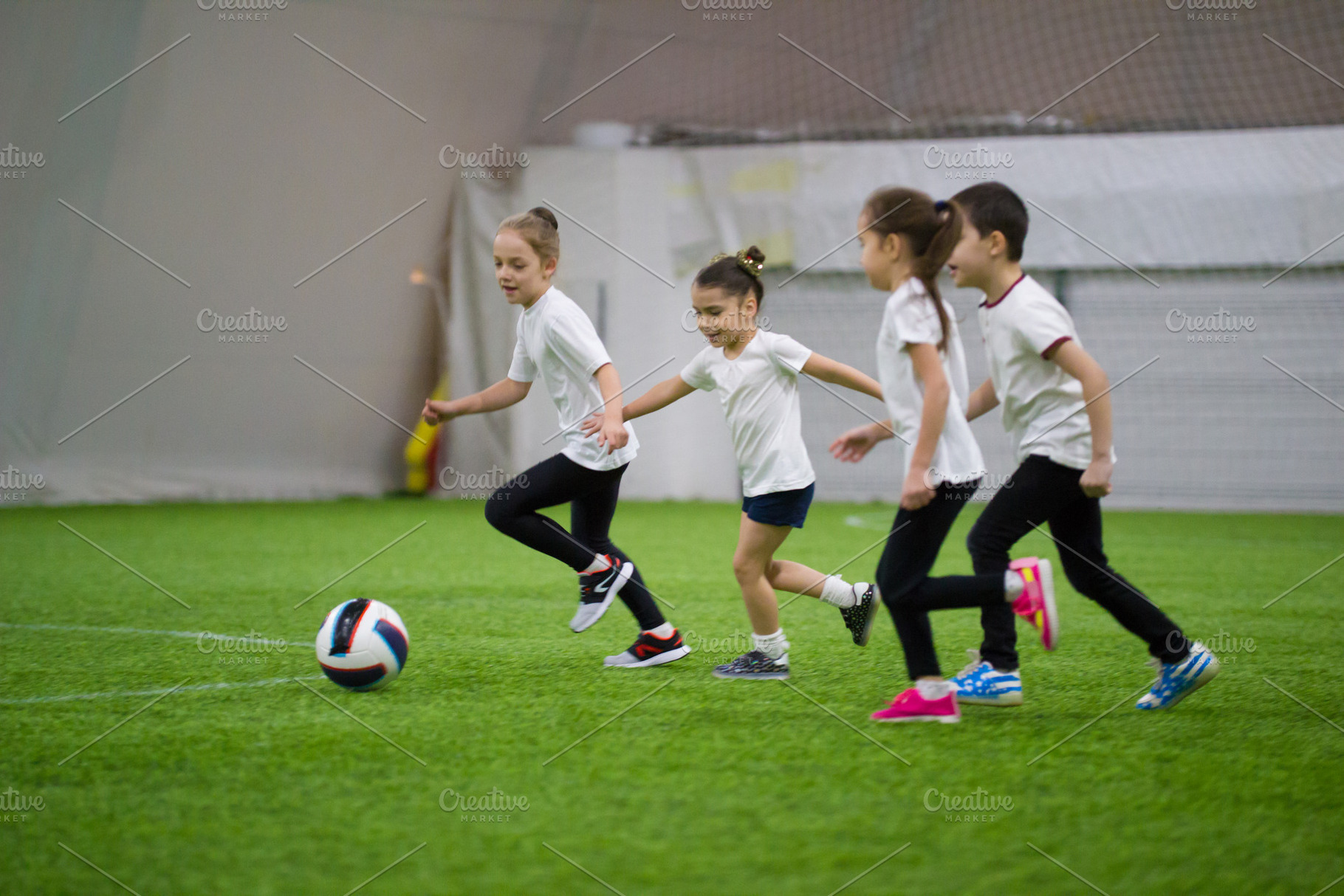Children playing football indoors, a Person Photo by Barcelona_dreams