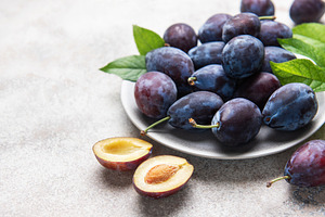 Fresh ripe plums, whole and halved on plate, a Food & Drink Photo by Olena Rudo