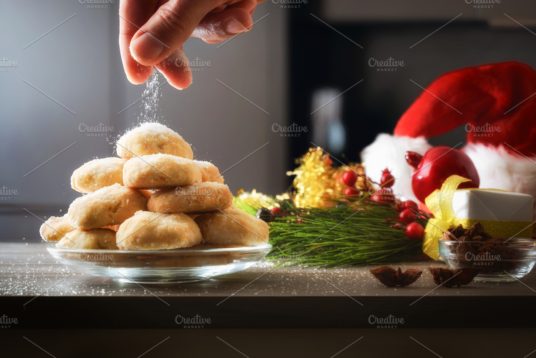 Hand sprinkling sugar over stack of cookies on kitchen bench, a Food & Drink Photo by Davizro's Market