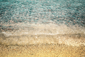 Sandy beach and transparent sea waves pebbles under the water stock photo