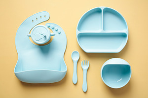 Set of silicone tableware for baby on pastel yellow background. Children food s