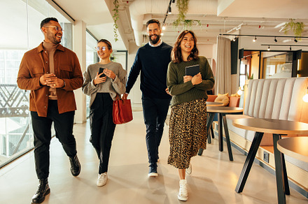 Multiethnic businesspeople walking through a modern office, a Person Photo by Jacob Lund