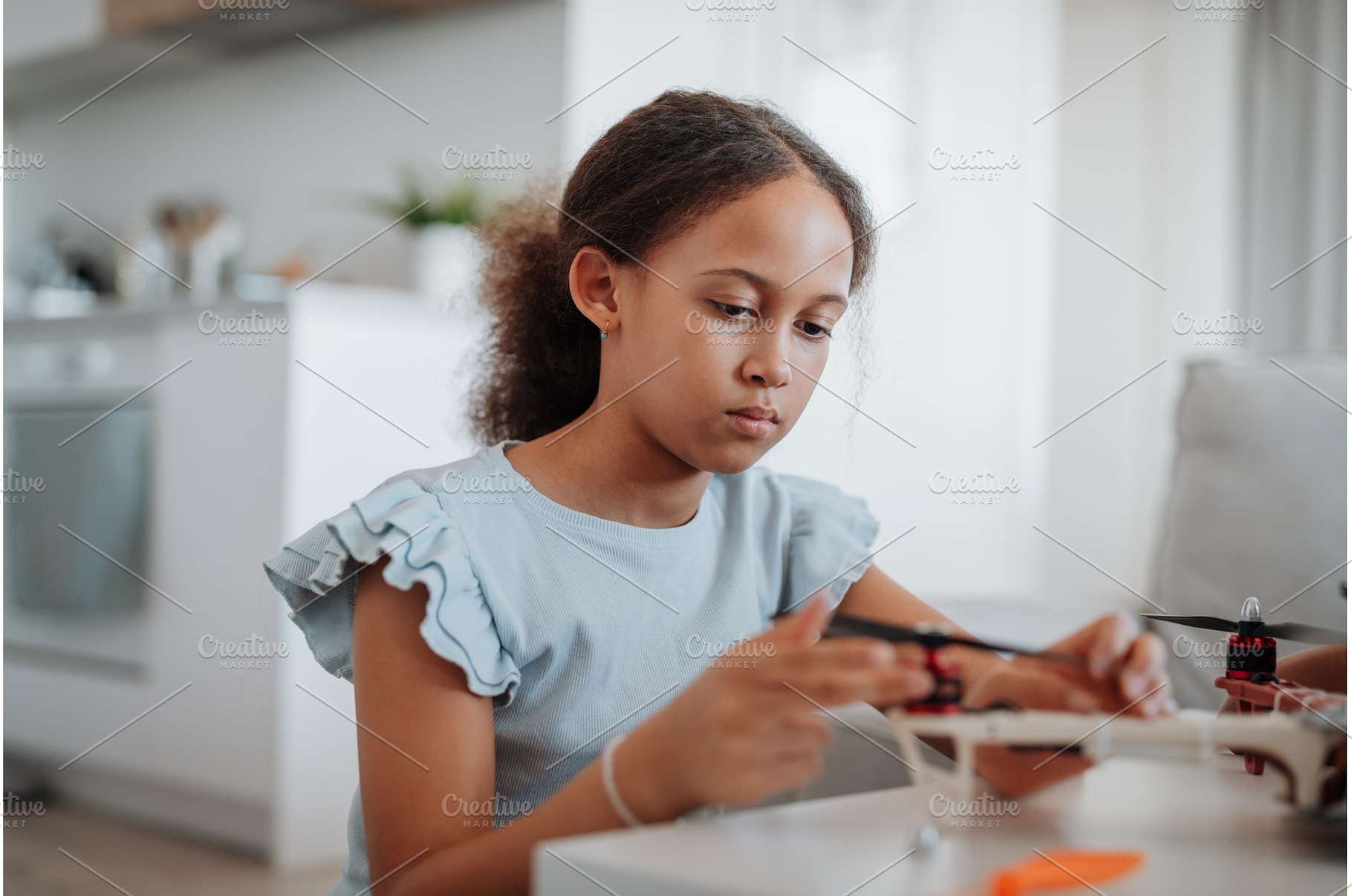 Focused girl working on small robot, a School & Education Photo by HalfPoint