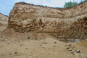 High cliff and quarry with exposure of layered rocks and sand, a Nature Photo by ndanko