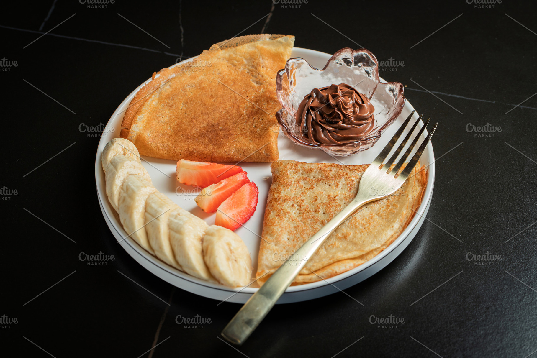 A plate of crepes filled with chocolate spread and topped with banana slices an, a Food & Drink Photo by Budarinphoto