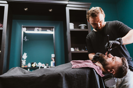 Barber shaves beard with straight razor for male client, a Person Photo by progressman