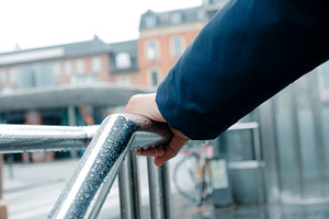 a man grips a rain-covered railing in Copenhagen, a Photo by Nito